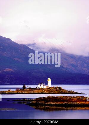 Phare sur Isle Ornsay, de la rive sud de l'île de Skye, en Ecosse. Navire de commerce à Rocky island, montagnes en arrière-plan Banque D'Images