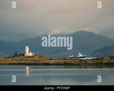 Phare sur Isle Ornsay navire de commerce.à rocky island, montagnes en arrière-plan. Île de Skye, Ecosse, Royaume-Uni. Banque D'Images