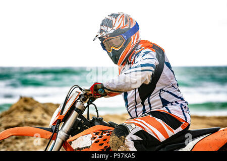 Motocycliste dans un vêtement de protection assis sur moto en face de la mer Banque D'Images