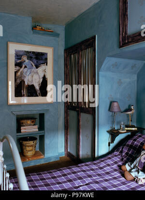 Grand tableau au-dessus de l'alcôve d'étagères dans la chambre de l'enfant bleu avec couvercle vérifié on bed Banque D'Images