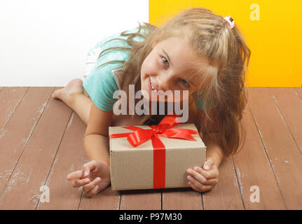 Cadeaux, shopping et présents - boîte-cadeau est lié à la jeune fille les mains sur un fond de bois. Banque D'Images