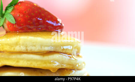 Pile de crêpes aux fraises sur le dessus et arrosé de sirop, gros plan macro. Banque D'Images