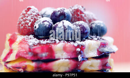 Pile de crêpes aux framboises, bleuets et arrosé de sirop de bleuet, gros plan macro. Banque D'Images