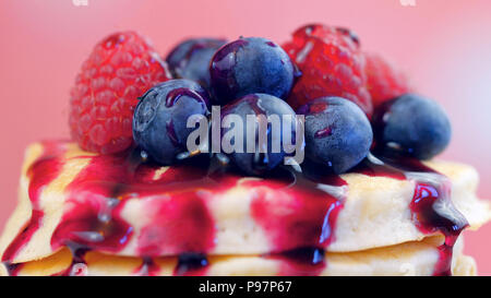 Pile de crêpes aux framboises, bleuets et arrosé de sirop de bleuet, gros plan macro. Banque D'Images