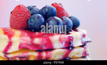 Pile de crêpes aux framboises, bleuets et arrosé de sirop de bleuet, gros plan macro. Banque D'Images