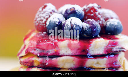 Pile de crêpes aux framboises, bleuets et arrosé de sirop de bleuet, gros plan macro. Banque D'Images