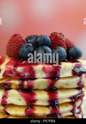 Pile de crêpes aux framboises, bleuets et arrosé de sirop de bleuet, gros plan macro. Banque D'Images