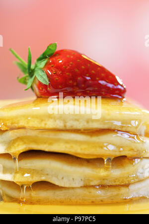 Pile de crêpes aux fraises sur le dessus et arrosé de sirop, gros plan macro. Banque D'Images