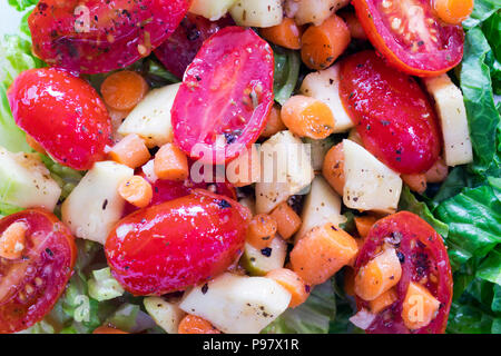 Extreme close up d'une salade verte avec tomates, carottes, courgettes, de la laitue romaine et l'ail dans une viniagrette de citron. Banque D'Images