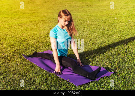 Une femme brune coach sportif dans une salle de sport et haut leggings offre une grande ficelle sur le tapis de yoga pour les mains sont soulevées vers le haut sur le tapis de yoga, part Banque D'Images