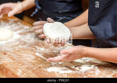 Close-up des mains des enfants la préparation de la pâte à pizza. La pizza, les enfants et le concept de la cuisine - les enfants faire la pizza. Banque D'Images