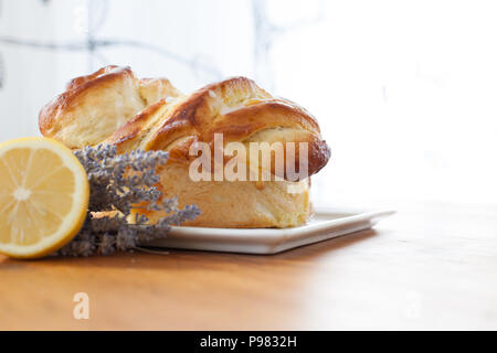 Brioche aux chinois à la crème sur une plaque sur une table en bois avec tranche de citron et lavande Banque D'Images