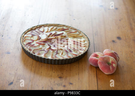 Tarte aux pêches / Peach Pie sur une table en bois avec trois pêches Banque D'Images