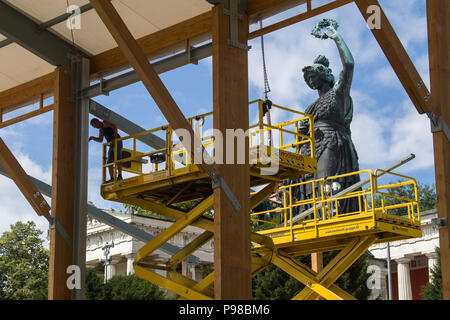 Munich, Allemagne. 16 juillet, 2018. Un travailleur fixation de la poutre du toit à poutres en bois la structure d'un chapiteau. Le Bavaria statue peut être vu dans l'arrière-plan. Cette année, l'Oktoberfest se déroule du 22 septembre au 07 octobre 2018. Crédit : Peter Kneffel/dpa/Alamy Live News Banque D'Images