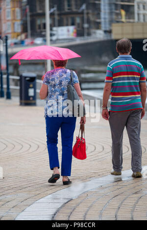 Pays de Galles Aberystwyth UK, lundi 16 juillet 2018 Royaume-Uni Météo : Après de nombreuses semaines de soleil presque constante et de temps exceptionnellement sec, les pluies sont revenues avec des gens à l'abri de l'averse vus sous leur parapluie comme ils marchent le long de la promenade à Aberystwyth, sur la côte ouest du pays de Galles Crédit photo : Keith Morris Alamy Live News Banque D'Images