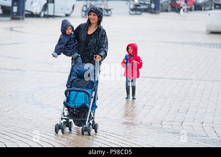 Pays de Galles Aberystwyth UK, lundi 16 juillet 2018 Royaume-Uni Météo : Après de nombreuses semaines de soleil presque constante et de temps exceptionnellement sec, les pluies ont repris avec une femme vu obtenir imbibé comme elle marche avec ses enfants le long de la promenade à Aberystwyth, sur la côte ouest du pays de Galles Crédit photo : Keith Morris Alamy Live News Banque D'Images