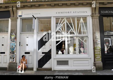 Jeune femme de manger une collation sur la porte à côté de la station de confort à Londres Banque D'Images