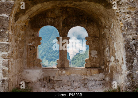 Une fenêtre voûtée au sommet de la forteresse de Jajce, qui permet d'admirer une cheminée d'une usine de fusion voisine Banque D'Images