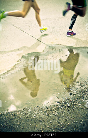 Les coureurs de marathon les jambes et reflet dans un bassin d'eau Banque D'Images