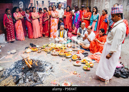 Lalitpur, Vallée de Katmandou, Népal : Des femmes habillées en rouge assister à une cérémonie à Kumbheshwor Temple (14ème siècle), le plus vieux temple à Patan. Banque D'Images