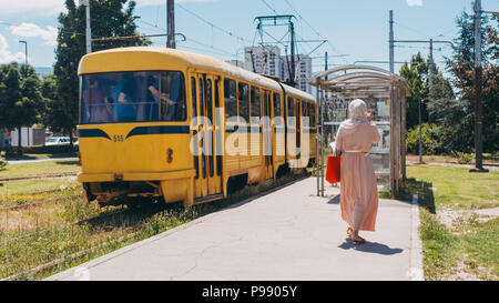 Une femme marche à bord d'un tramway T3 Tatra jaune à un arrêt de tram dans la banlieue de Sarajevo, Bosnie-Herzégovine Banque D'Images