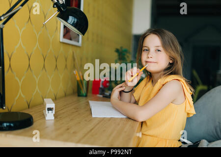 Photo de fille avec crayon et notebook sitting at table Banque D'Images