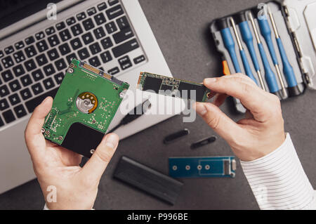 L'homme se prépare à remplacer un vieux lecteur de disque dur avec un moderne M.2 SSD dans son ordinateur portable Banque D'Images