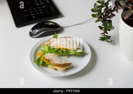 Sandwich de pain frais avec du fromage et de la salade sur lieu de travail. Le déjeuner de travail Banque D'Images