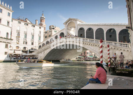 L'Europe, Italie, Vénétie, Venise. Les personnes prenant reste à river bank Canale Grande (Grand Canal) près de Ponte di Rialto (Pont du Rialto à Venise). Banque D'Images