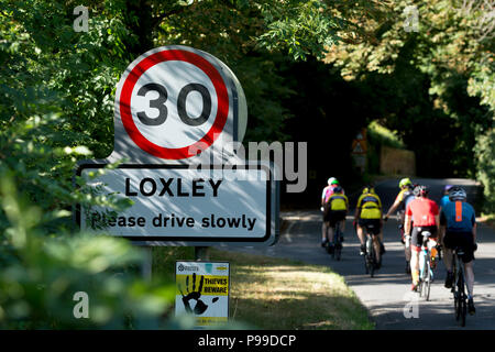Un groupe de cyclistes passant Loxley panneau du village, Warwickshire, England, UK Banque D'Images