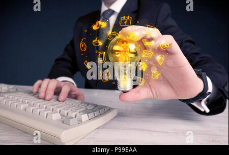 Un bureau commercial promouvoir ses idées de concept avec l'illustration des médias en ligne et les logos de l'appareil autour de l'ampoule en verre électrique. Banque D'Images