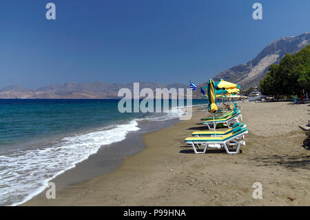 Des fauteuils-lits de soleil et parasols, Mirtéai Beach, Kalymnos, îles du Dodécanèse, Grèce. Banque D'Images