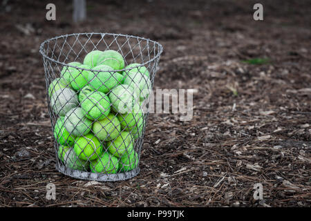 Balles de tennis s'est évanoui ancienne entassés dans le panier métallique placé sur le sol avec copie espace Banque D'Images