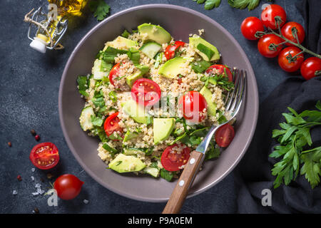 La nourriture végétalienne. Salade de quinoa aux épinards, d'avocat et les tomates de pierre sombre tableau. Close up. Banque D'Images