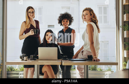 Portrait de quatre jeunes femmes ensemble dans Office. Groupe de multi-ethnic businesswomen looking at camera. Banque D'Images