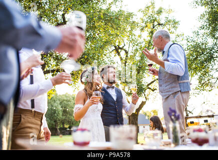 Un homme faisant discours à réception de mariage à l'extérieur à l'arrière-plan. Banque D'Images