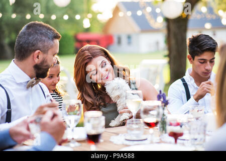 Les clients avec un petit chien assis à la table à l'extérieur dans la cour. Banque D'Images