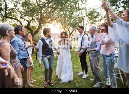 Mariée, le marié et les invités à votre réception de mariage à l'extérieur dans la cour. Banque D'Images