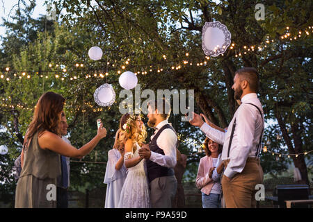 Les clients avec les smartphones de prendre photo de mariés à réception de mariage à l'extérieur. Banque D'Images