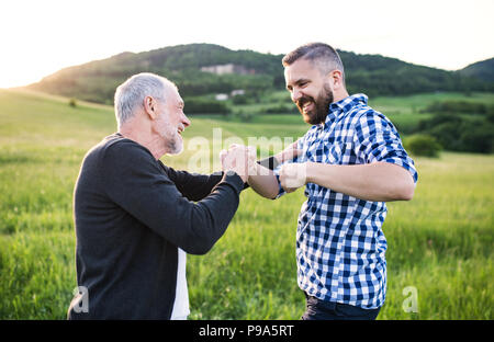 Un adulte avec des fils hipster père faisant fist bump dans la nature au coucher du soleil. Banque D'Images