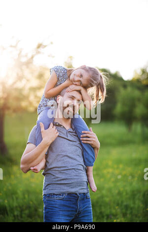 Petite fille un père donnant piggyback ride au printemps la nature. Banque D'Images
