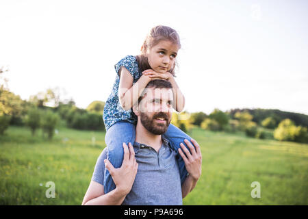 Petite fille un père donnant piggyback ride au printemps la nature. Banque D'Images