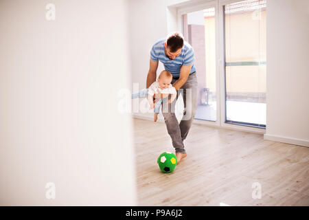 Jeune père de famille avec un petit garçon à la maison en jouant avec une balle. Banque D'Images