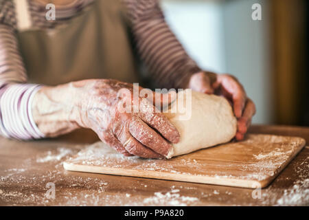 Un unrecognizale senior woman kneading dough dans la cuisine à la maison. Banque D'Images