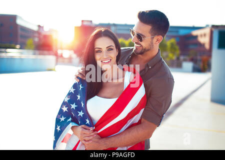 Heureux l'homme jeunes trendy couvrant petite amie avec USA flag Banque D'Images