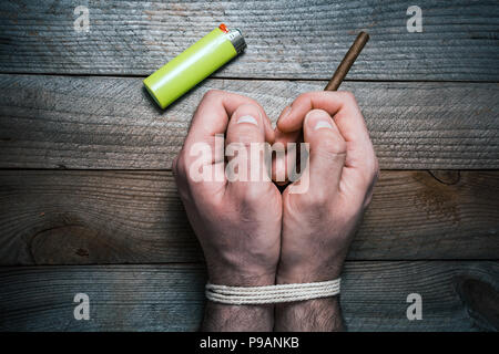 Cesser de fumer Concept avec 2 mains attachées sur une table en bois à côté d'un briquet. La main droite tient une cigarette Banque D'Images
