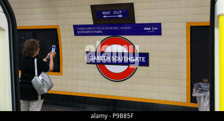 La station de métro Southgate. Le nord de Londres. UK 17 Juillet 2018 - Une femme prend une photo de l'affiche sur son téléphone mobile. L'échelon local, national et international de personnes visitent la station de métro Southgate pour prendre des photographies de la nouvelle enseigne qui a été fait en l'honneur de l'Angleterre football manager, Gareth Southgate comme l'équipe nationale anglaise de football a terminé quatrième à la Coupe du Monde en Russie. Le signe qui remplace 'Southgate" au cours de la London Transport logo est pendant 48 heures seulement. Credit : Dinendra Haria/Alamy Live News Banque D'Images