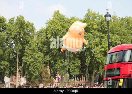 TRUMP STOP" au Parlement Square Gardens- 'Bébé' Trump gonflable géant s'élève au-dessus de la foule comme London bus rouge voyages par.Londres, Royaume-Uni. Banque D'Images