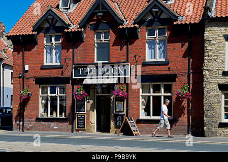 Homme marchant passé le Buck Inn, Thornton-le-Dale, North Yorkshire, England UK Banque D'Images