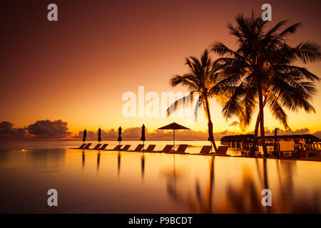 Piscine De luxe dans un magnifique coucher du soleil. Vacances d'été de luxe et maison de concept et design. La piscine tropicale design voyage Banque D'Images